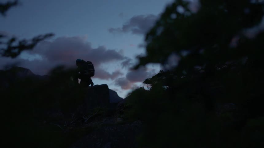 A man is crouching up on the rocks ahead