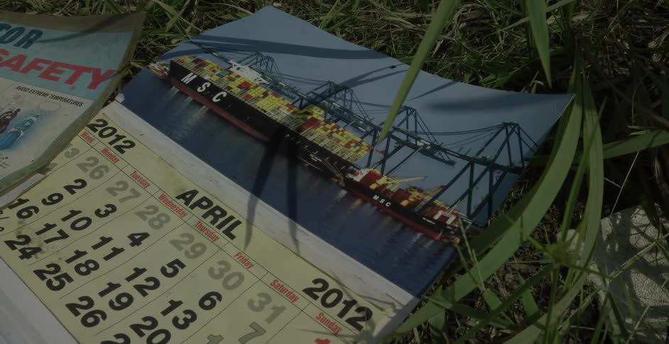 Old calendar picturing freight ship laying in grass on windy day