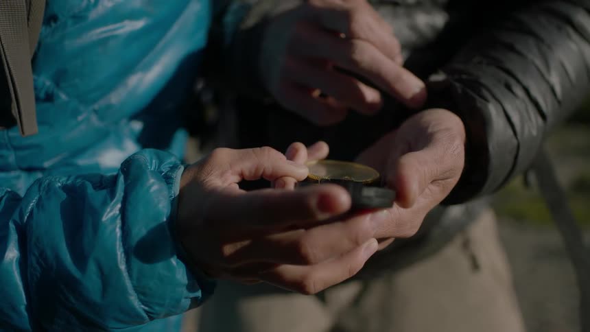 Two people hold and look at a compass together