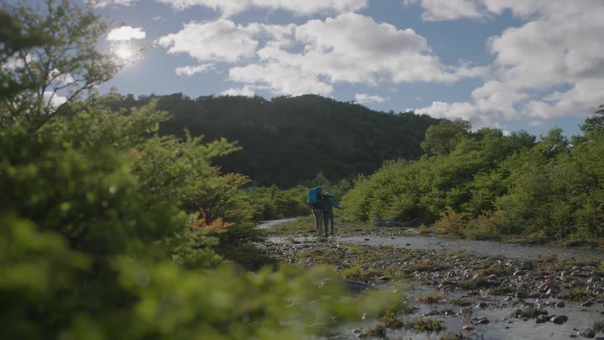 Two hikers cross a stream in the wilderness
