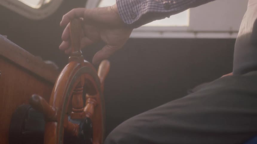 A man turns the wheel on his ship