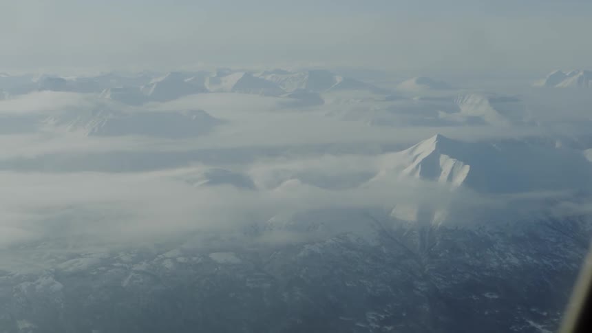 Aerial view above clouds of a large range of mountains