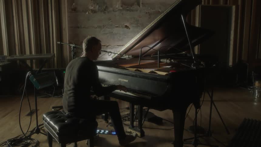 Man plays a piano while sitting on a bench