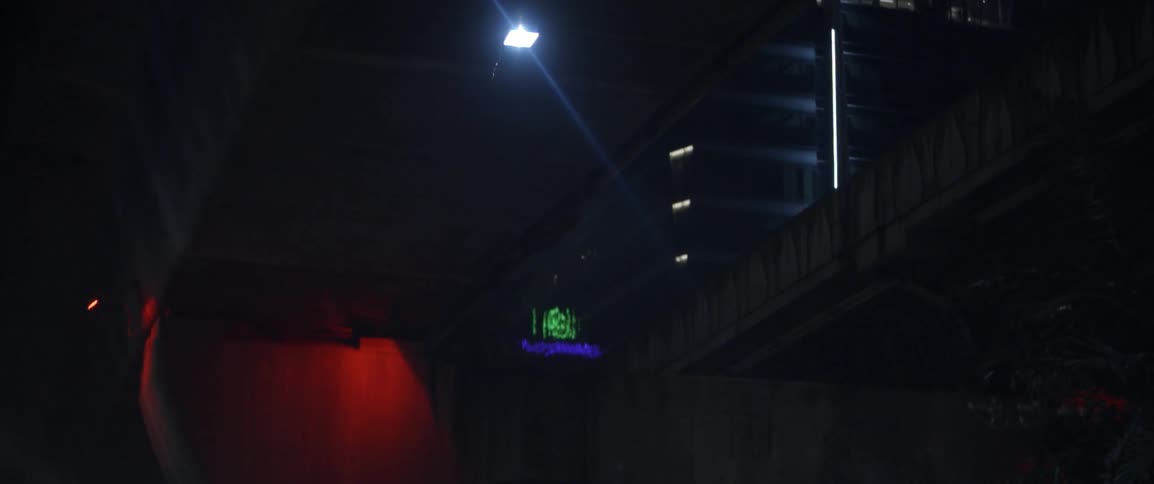 Lights hang below a bridge above a road at night