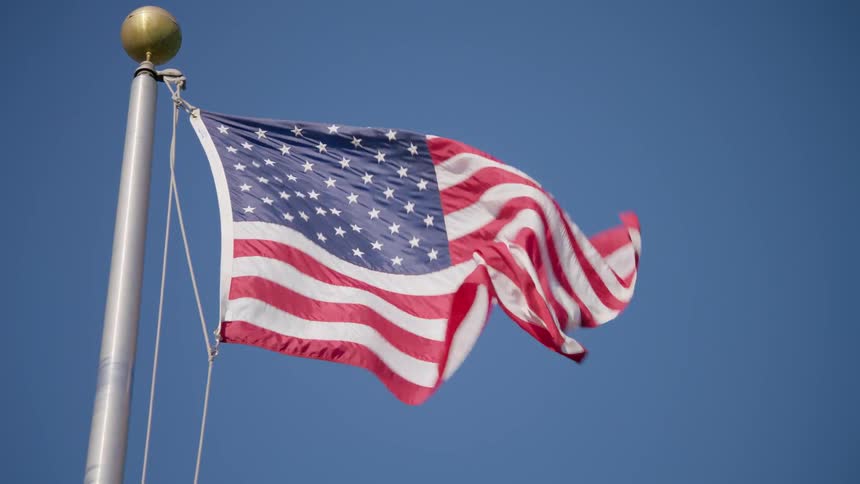 A large american flag flies in the wind