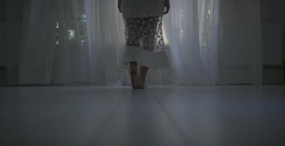 A woman's legs covered in sheer lace walks towards the window