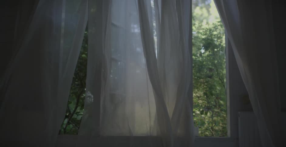 Curtains are blowing in the breeze of an open window