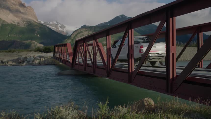 A truck crosses a river bridge in the mountains