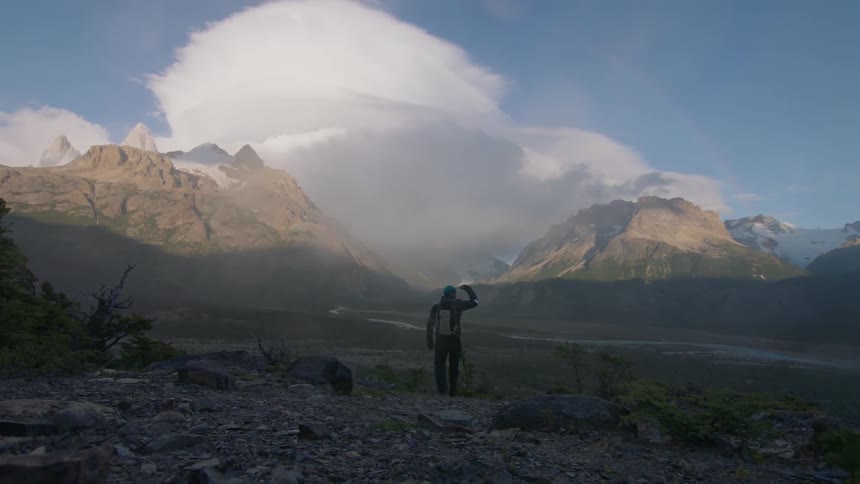 A man looks toward a mountain on a windy day