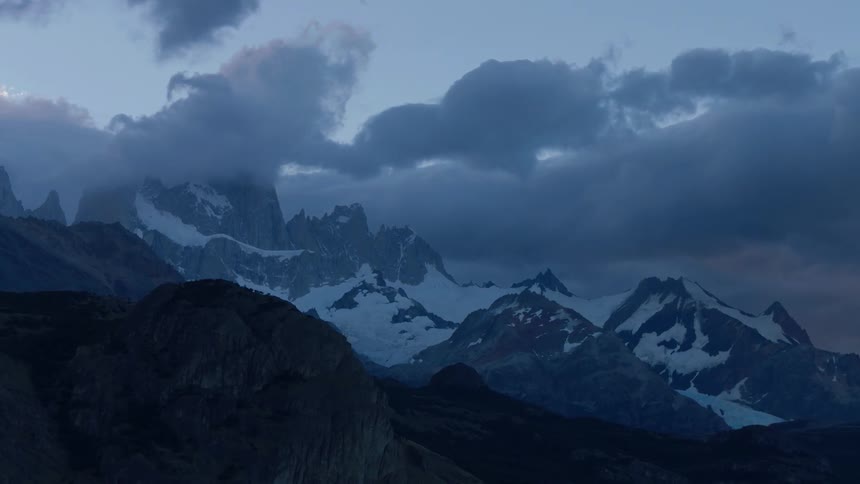 Clouds float over snowy mountain peaks