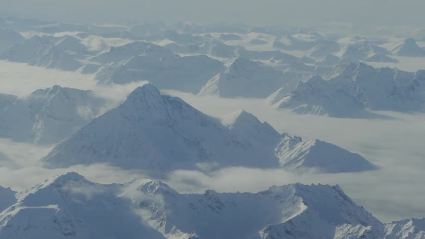 A mountain shown from a plane is covered in snow