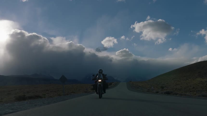 A person rides a motorcycle on a long empty road