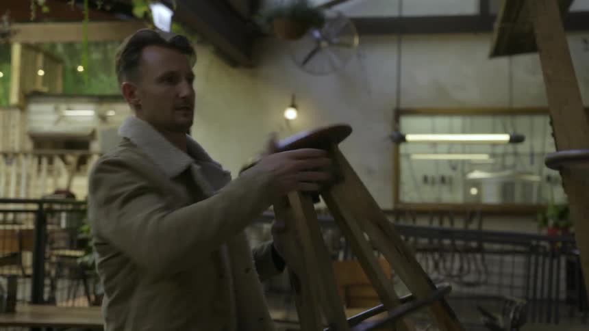 A man takes stools off a table