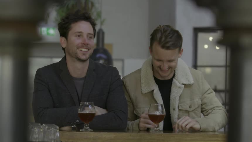 Two men talking and laughing in a bar