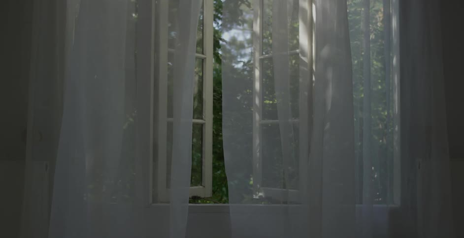 Curtain blowing in the wind with the window partially open
