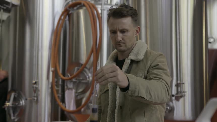 Man pours liquid in a tube in a bowl and examines it