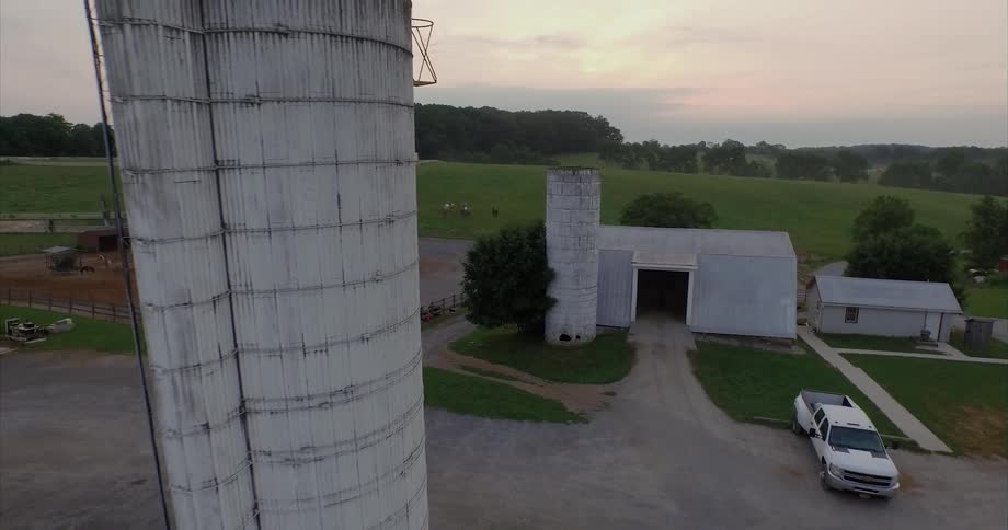 A couple silos stand next to farm buildings