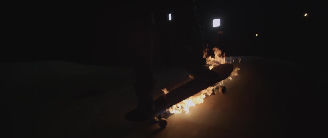 Person rides on a skateboard lit on fire at night