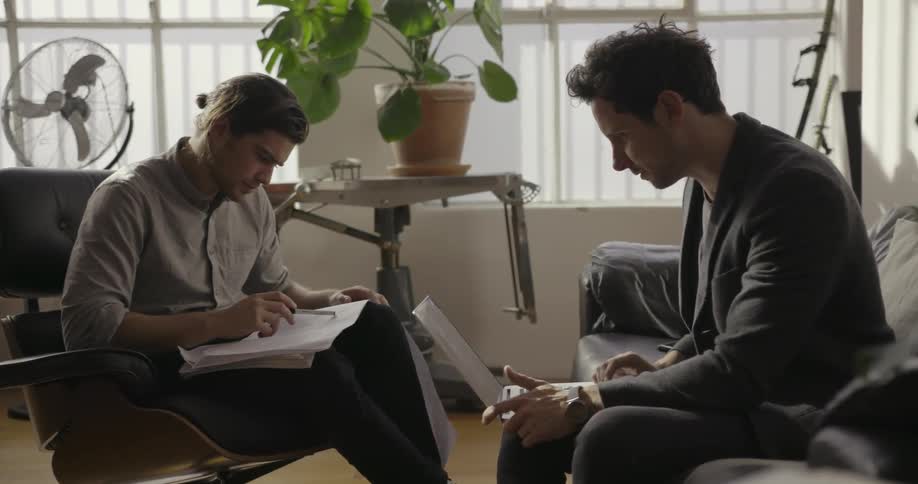 Two men talk while going over documents