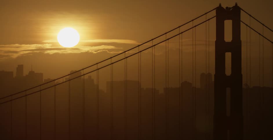 The sun sets over a city bridge