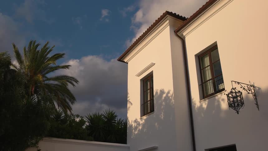 Clouds pass over a home and palm trees