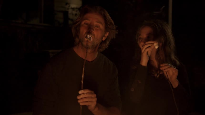 Man and girl roast marshmallows over a campfire at night