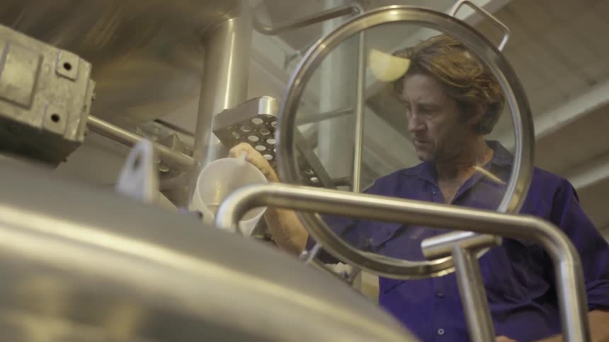 A man pours a liquid into a piece of equipment