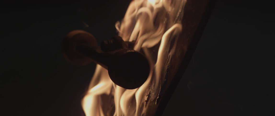 Close up of a skateboard on fire as it falls over