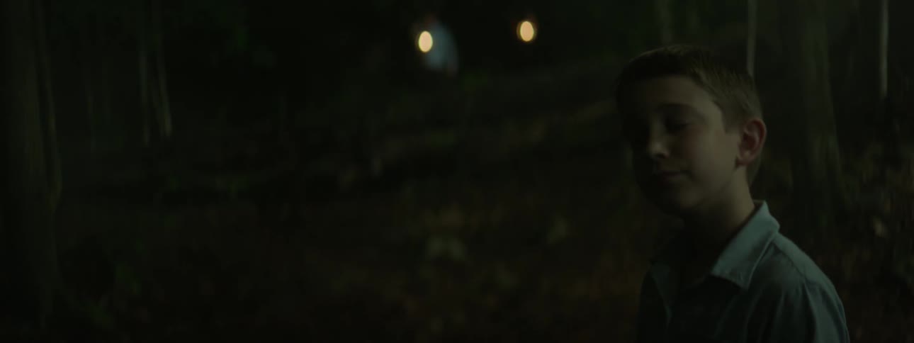 Child stands and turns head in dim light