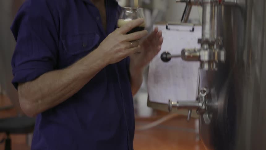 A man tests a drink from a vat
