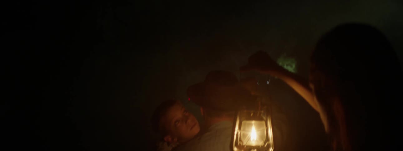 Person holds a lantern illuminating a man carrying a child
