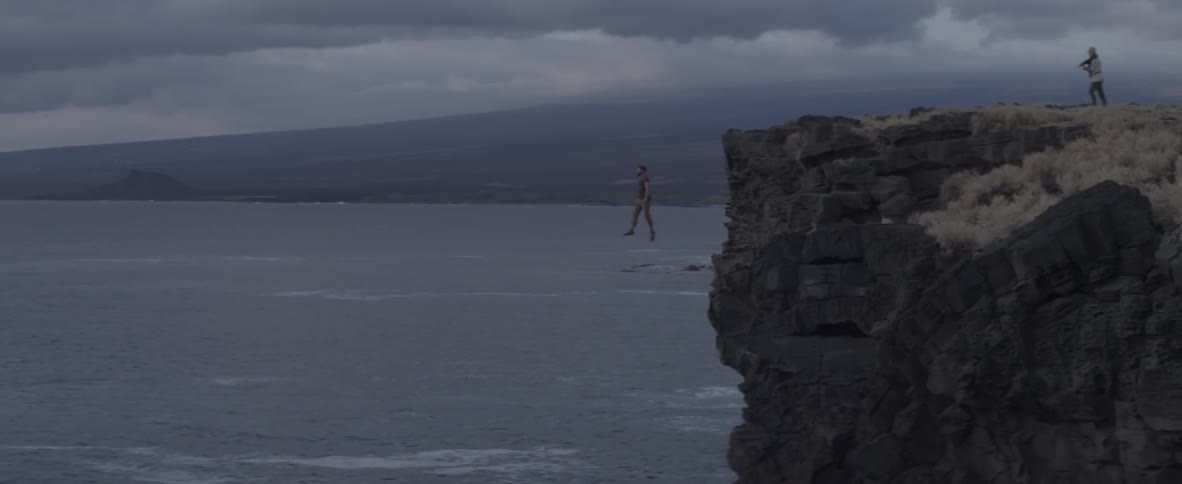 A man stands on the edge of a cliff and then jumps off