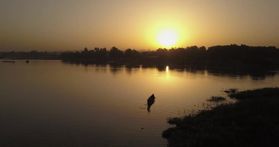 A single boat is traveling in the water at dawn