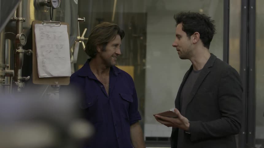 Two men are in a factory discussing something on a tablet pc