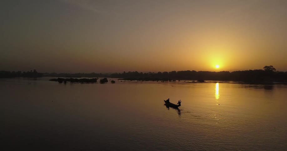 People are rowing a canoe at sunset