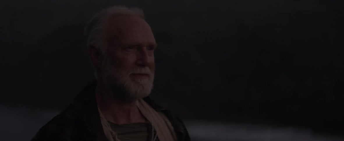 Elderly man smiles in dim light