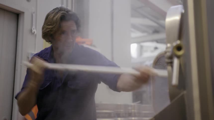 Man cleans machinery using a long handled mop