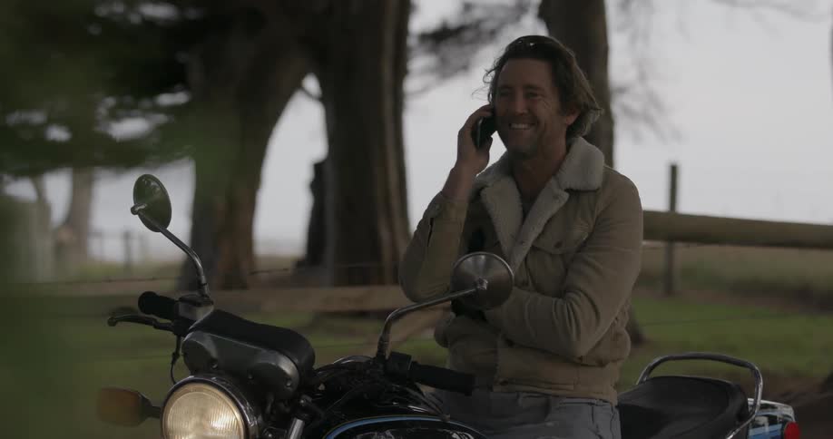 A man talks on his phone as he sits on his motorcycle