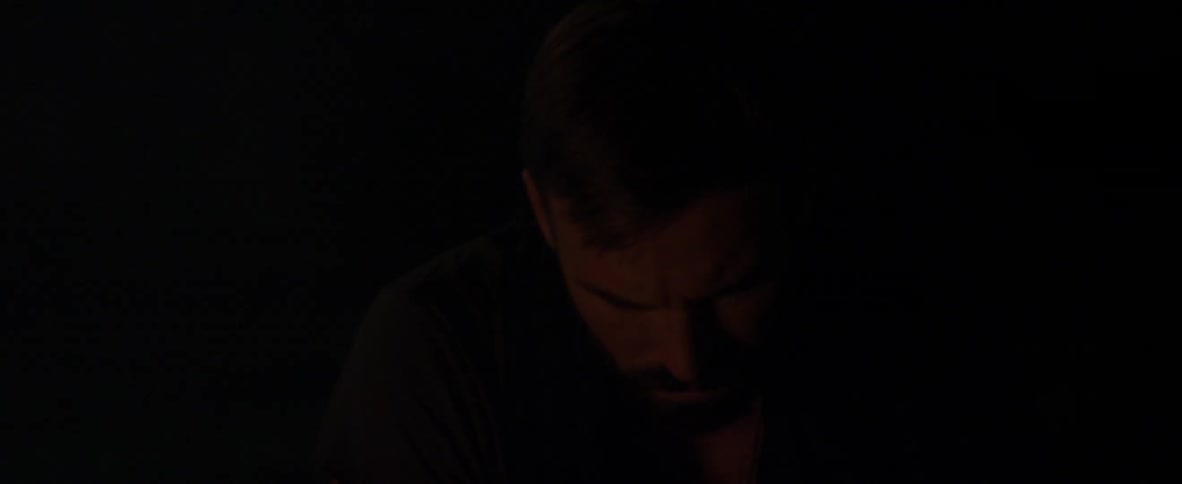 Man's face looking down in dim light