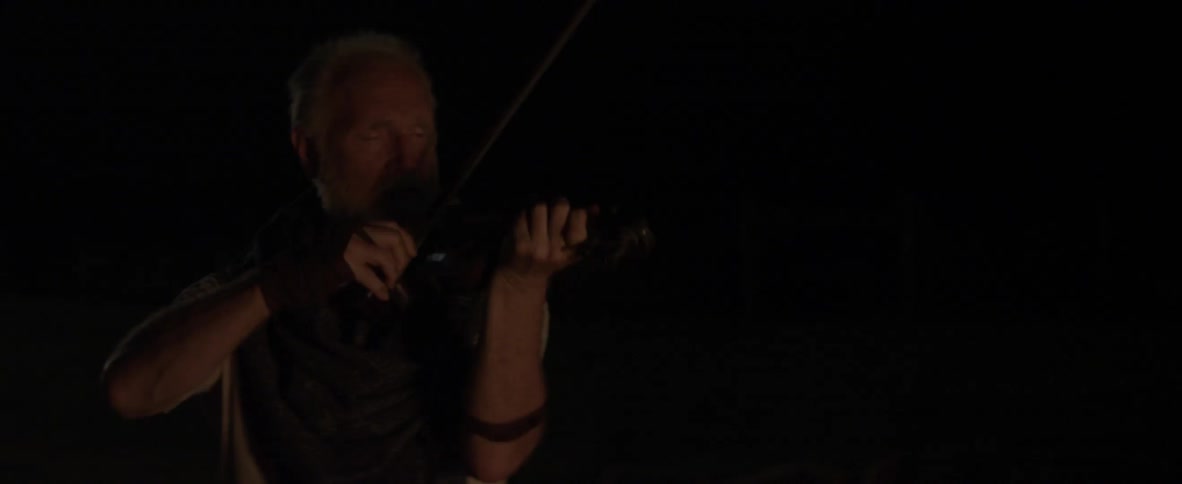 A man plays a violin in the dark