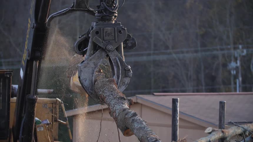 A crane is moving a log onto the stack