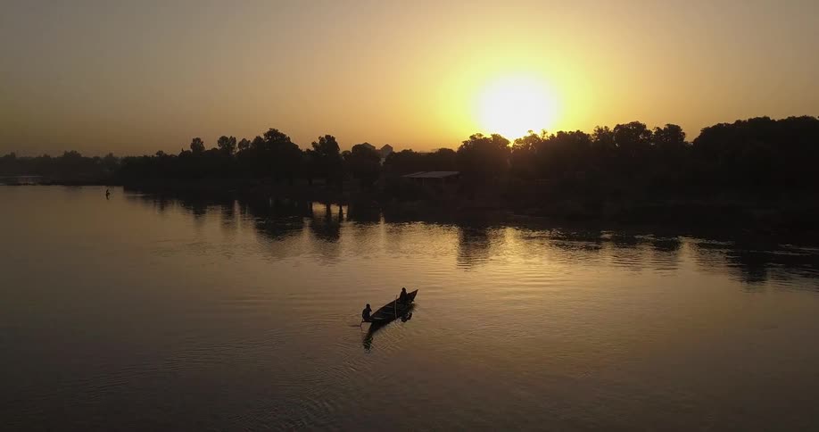 People paddle a boat at sunset