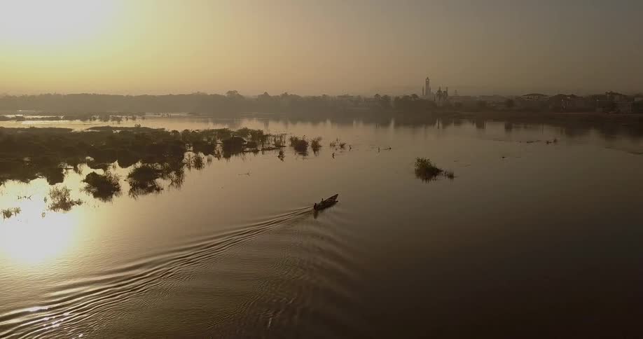 Boat floats down a river at sunset