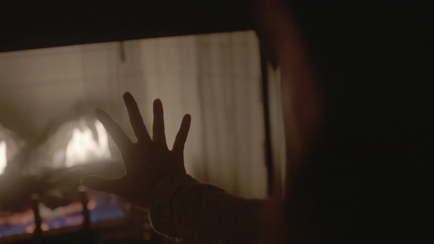 A person warms their hands by a fire