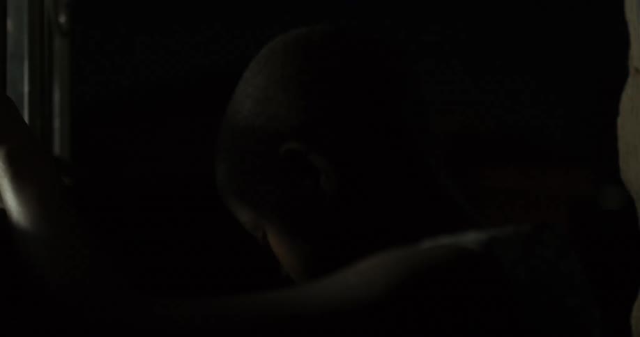 A boy opens a door inside a dark building