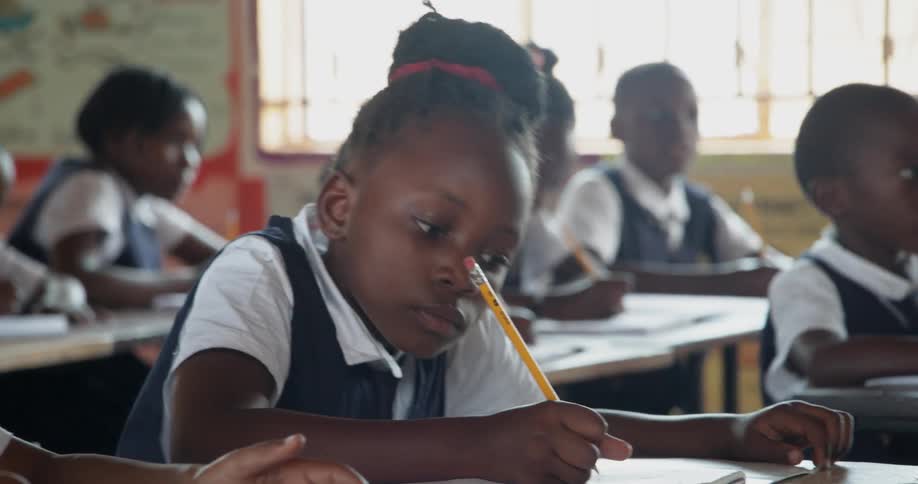 Children sitting in a classroom writing