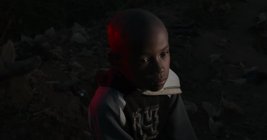 Sad child sitting outside at night