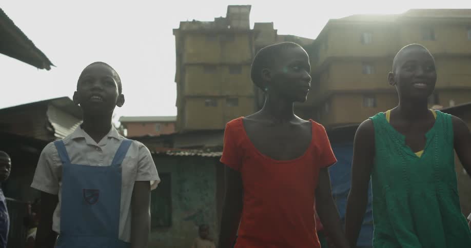 Three children walk down an alley on a sunny day