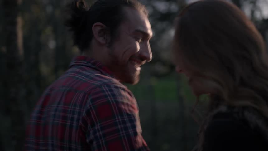 A man and woman laugh as they walk in the woods