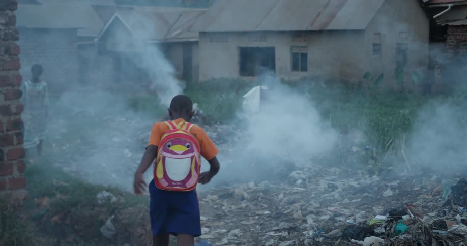Child walking over garbage and piles of smoke
